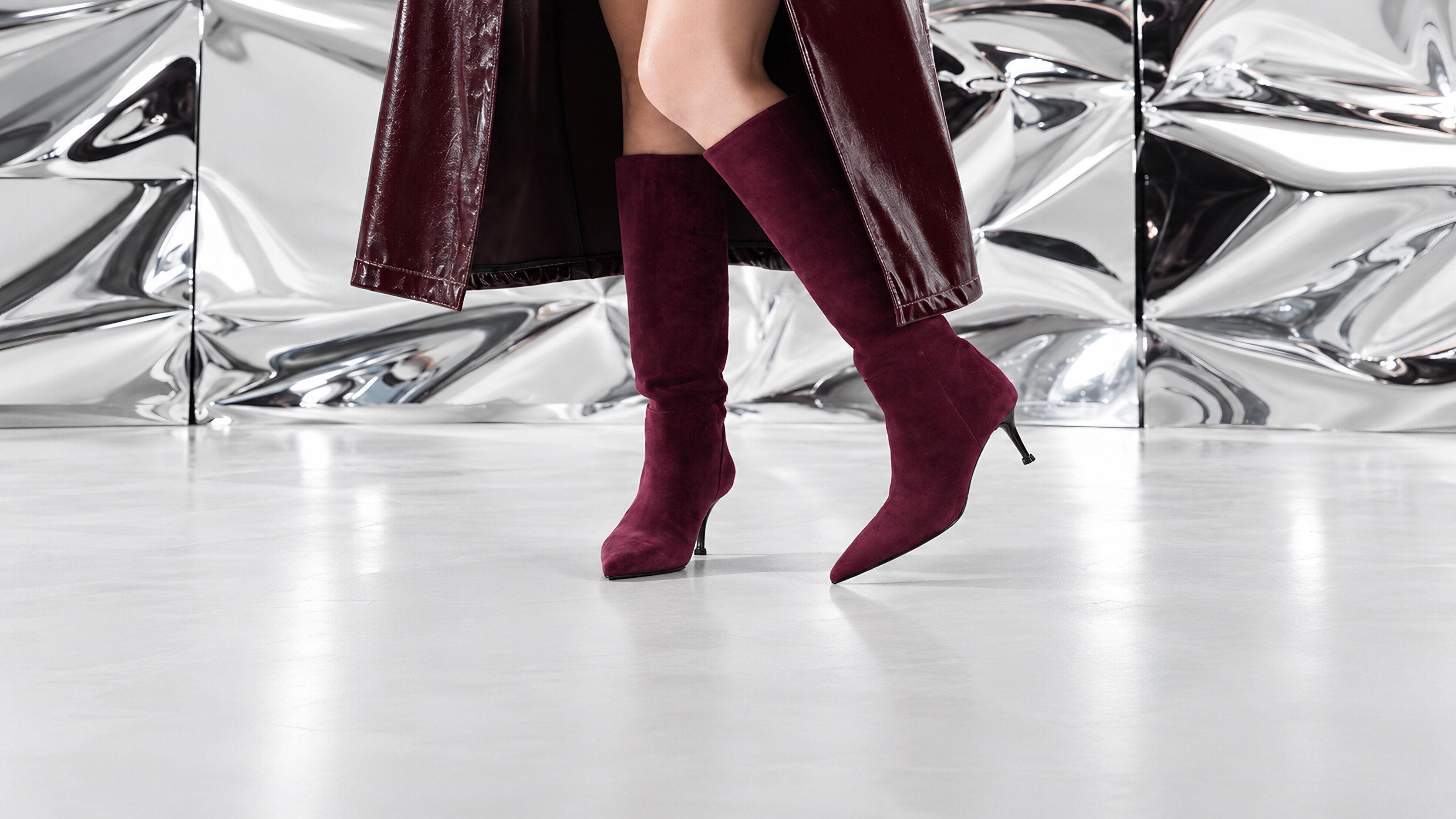 Burgundy suede knee-high boots against a chrome backdrop